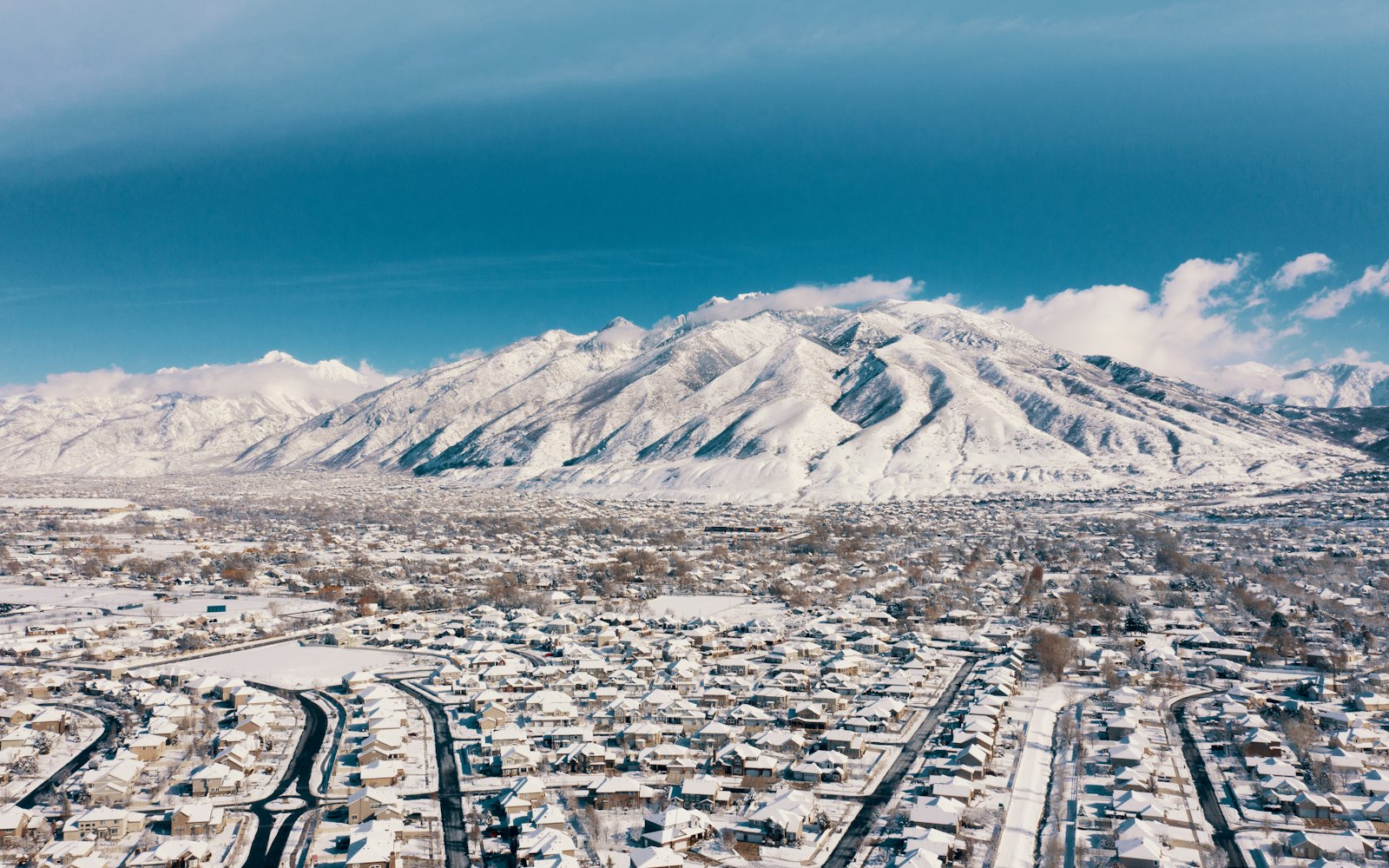 Aerial view of a snowy Utah neighborhood below the mountains