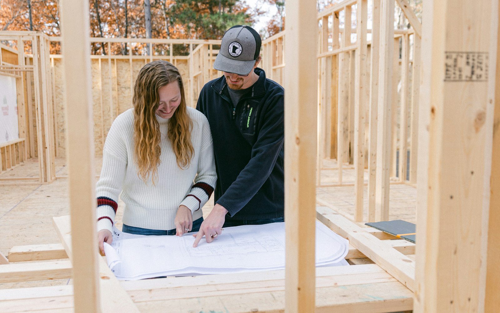 A couple reviewing plans inside a newly framed house